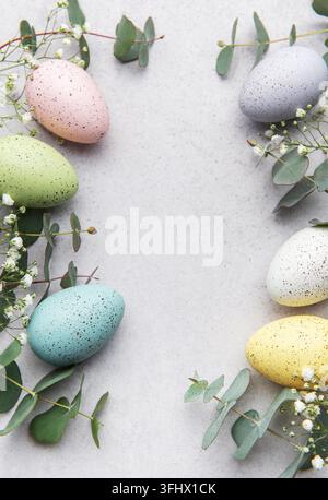 Easter eggs and eucalyptus leaves forming a frame on gray background Stock Photo