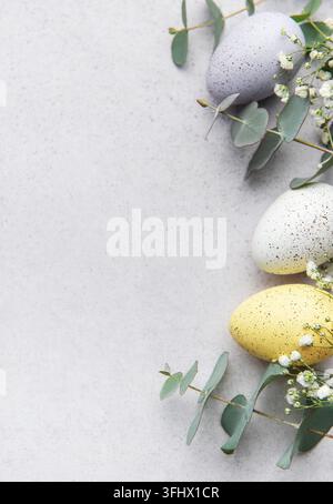 Easter eggs and eucalyptus leaves forming a frame on gray background Stock Photo