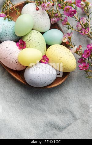 Easter decor. Colored Easter eggs on a wooden plate on the table. Stock Photo