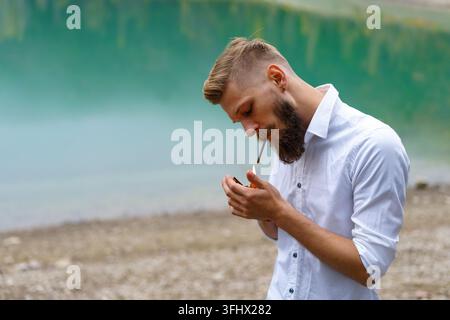 Handsome serious guy, young thoughtful man smokes, heating tobacco products Stock Photo