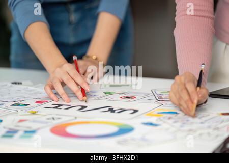 Two designers engaged in a collaborative UX and UI design session, sketching ideas and discussing user experience improvements. Stock Photo