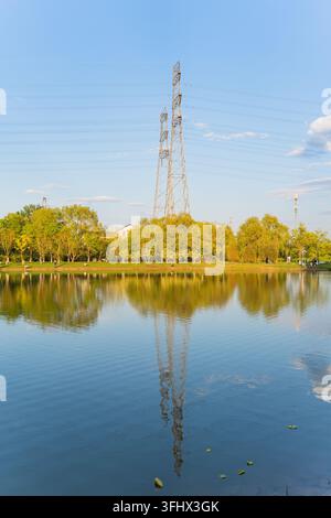Vertical shot of transmission tower and tree reflections on park lake surface Stock Photo