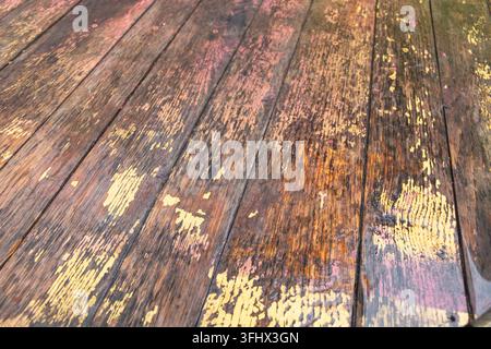 Weathered wooden planks with peeling yellow and pink paint forming a rustic textured background. Stock Photo