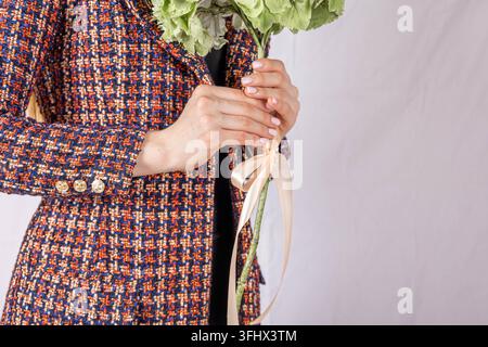 Close-up of woman's hand on tweed jacket holding flower Stock Photo