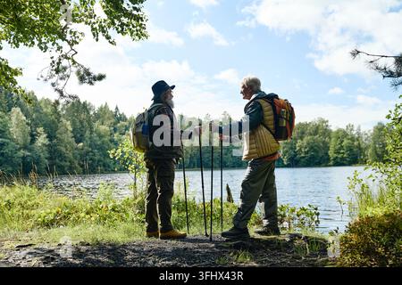 Senior Men Hiking with Trekking Poles near Lake in Forest Stock Photo