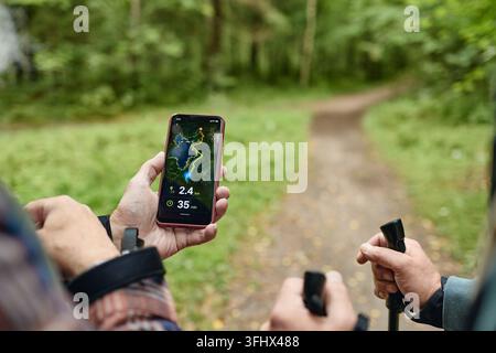 Senior Men Using Navigation App on Smartphone While Hiking in Forest Stock Photo