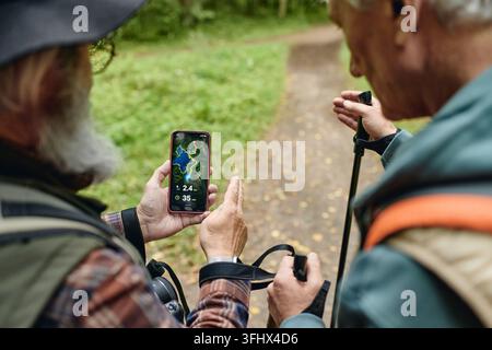 Senior Men Using Navigation Map App on Smartphone While Hiking Stock Photo