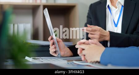 Two professionals analyze data on a tablet, discussing strategies for business growth in a contemporary workspace. Stock Photo