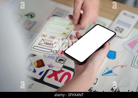 Two designers collaborate on a UX UI project, using a smartphone and sketches to enhance user experience. Stock Photo