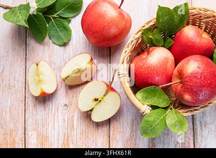 Fresh red apples in basket and sliced on wood Stock Photo