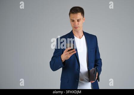 A male businessman in a blue jacket holds a phone in his hand Stock Photo