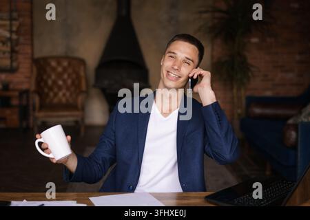 Confident man sitting on desk taking break from working with electronic Stock Photo
