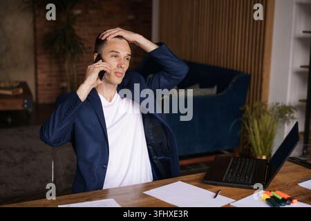 Very busy. Confident successful man in jacket working on laptop and talking Stock Photo