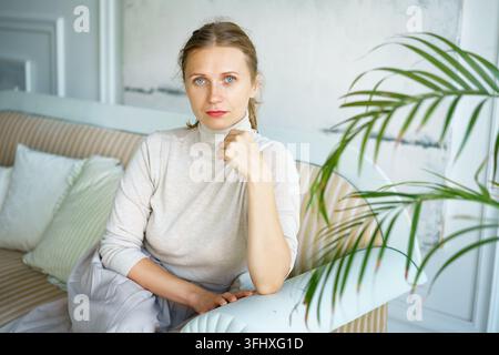 Portrait of a beautiful woman sitting on a sofa in a bright room Stock Photo