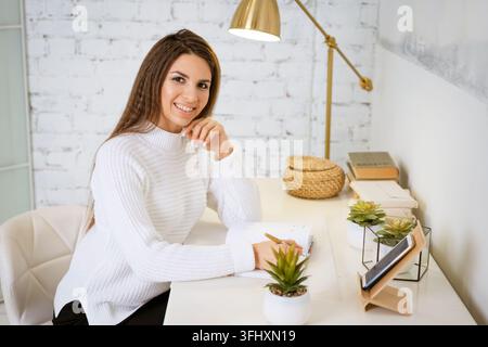 Business woman writes in a notebook while sitting at the table Stock Photo