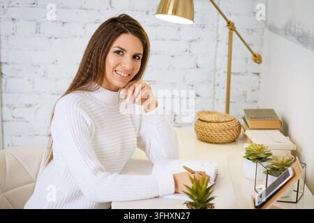 Business woman writes in a notebook while sitting at the table Stock Photo