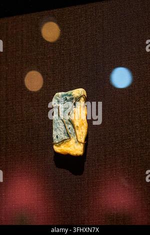 A blue-green and bright-yellow two-color mineral pendant, wrapped and fixed with copper wire, and light spots embellish the dark display background. Stock Photo