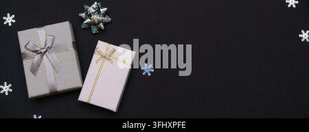 Gift boxes and snowflakes on dark paper black background. Christmas gift. Stock Photo
