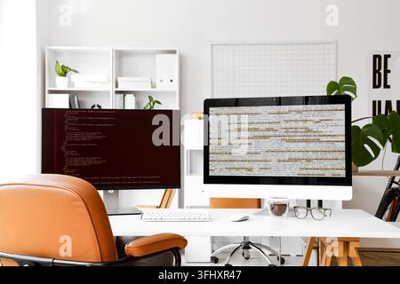 Software development and coding, programmer workspace with dual monitors displaying source code in a modern home office environment Stock Photo