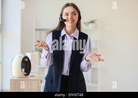 Customer support and remote communication, friendly call center agent wearing headset talking to client in modern office environment Stock Photo