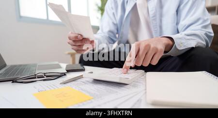 Financial Management. Man reviewing receipts and using calculator for budgeting. Stock Photo