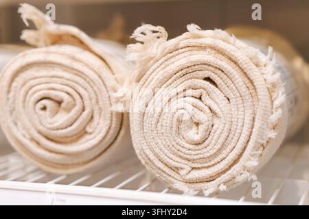Two white towels are rolled up and placed on a shelf Stock Photo