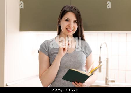 A woman is smiling and holding a book in her hand Stock Photo
