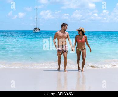 Couple walking hand in hand along the serene shores of Anse Georgette, Praslin Seychelles Stock Photo