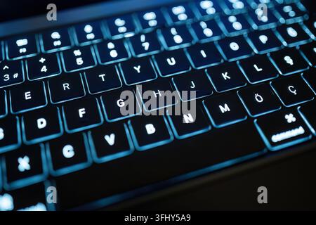Blue illuminated laptop keyboard representing technology, programming, cybersecurity and digital communication Stock Photo