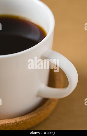 Close-up detail of black coffee in white ceramic cup and coaster Stock Photo