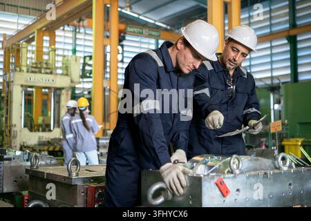 Industrial engineers and technicians discussing machine operation while inspecting equipment in a manufacturing factory Stock Photo