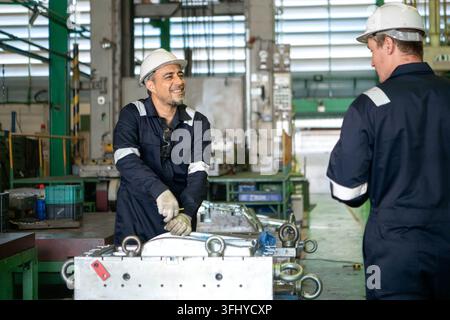 Industrial engineers and technicians discussing machine operation while inspecting equipment in a manufacturing factory Stock Photo