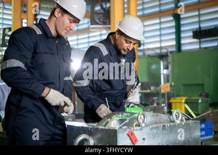 Industrial engineers and technicians discussing machine operation while inspecting equipment in a manufacturing factory Stock Photo