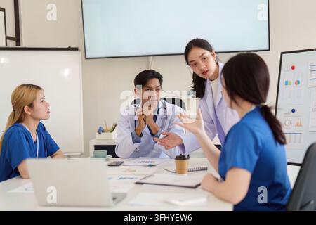 A diverse group of healthcare professionals engaged in a collaborative meeting, focusing on patient care and treatment plans in a contemporary setting Stock Photo