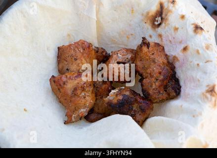 Charcoal-grilled pieces of meat lay in pita bread Stock Photo