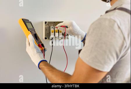 Close Up of Electrician Testing Circuit Breaker Panel With Multimeter Indoors Stock Photo