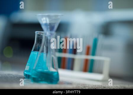 Young Middle Eastern and Arab medical technicians and doctors working together in a clinical blood testing laboratory, handling blue reagents, beakers Stock Photo