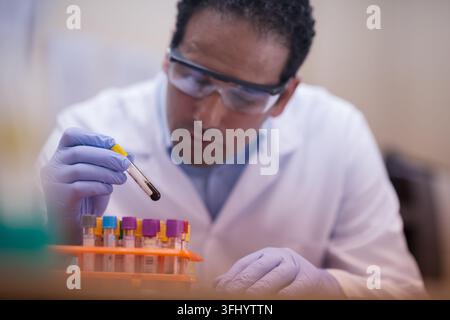 Lab technician carefully handling blood test sample in clinical laboratory wearing gloves and goggles Stock Photo