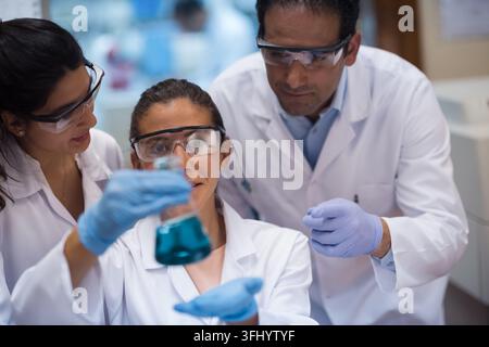Middle Eastern and Arab doctors with a lab technician collaborate on blood testing, examining samples and reagents in a clinical laboratory while wear Stock Photo