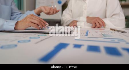 Colleagues collaborating on financial data, analyzing charts and reports for strategic business decisions. Stock Photo