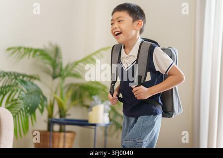 Excited Asian boy carrying backpack ready for back to school season at home Stock Photo