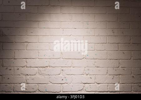 Textured white brick wall lit by a soft overhead spotlight, ideal as a backdrop for coworking, startup and creative office scenes, presentations, web Stock Photo