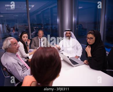 Middle Eastern business team meeting in a modern corporate office discussing strategy around a conference table Stock Photo