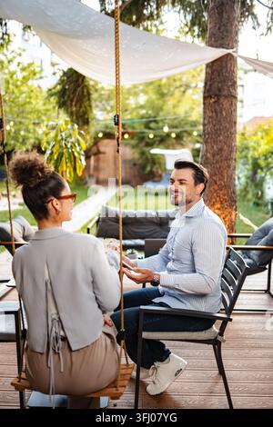 Couple sitting outdoors talking and smiling in garden Stock Photo