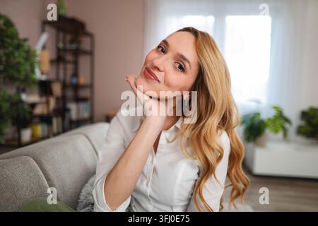 Woman smiling and relaxing on sofa at home Stock Photo