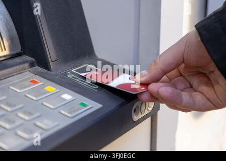 Person uses a contactless payment card at an ATM terminal, highlighting effortless money management and secure digital banking convenience during a ro Stock Photo