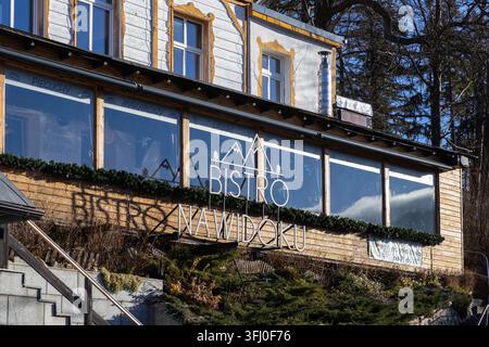 Szklarska Poreba, Poland - December 18, 2025: This rustic alpine restaurant offers a scenic outdoor seating area reflecting bright sunlight in a peace Stock Photo
