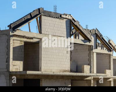 An unfinished multi-level house frame built from aerated blocks and timber roof beams, showcasing the structural phase of a housing investment and gen Stock Photo