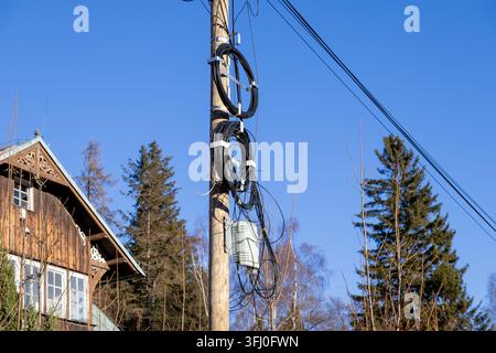 Fiber optic distribution equipment mounted on a wooden post beside a residential home, showing modern network connectivity infrastructure integrated i Stock Photo