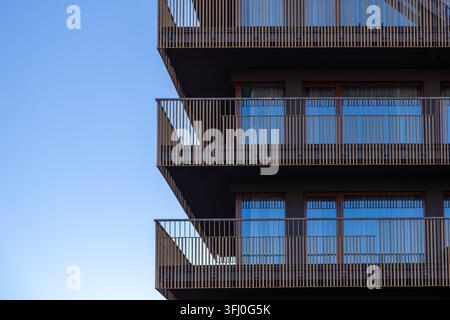 Minimalist architectural patterns on a contemporary apartment exterior, where repetitive metal slat balcony barriers create a geometric aesthetic for Stock Photo
